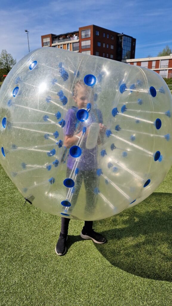 Een kind in een bubbelbal op het veld tijdens de jubileumdag van ADOS