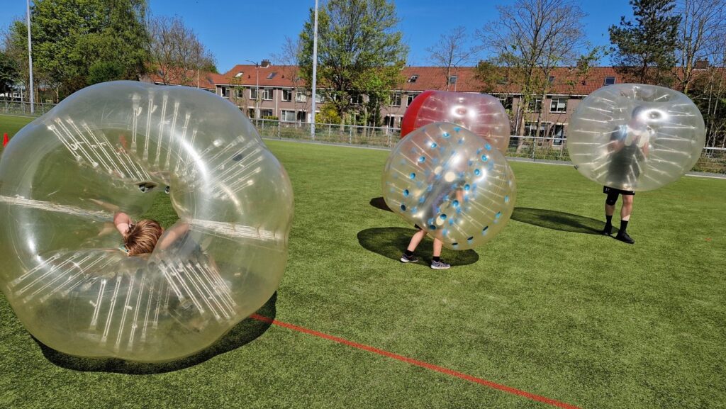 Deelnemers spelen bubbelvoetbal op het veld tijdens het 50-jarig jubileum van ADOS